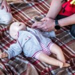 Ratownik medyczny ćwiczy resuscytację niemowlęcia na fantomie na dworze