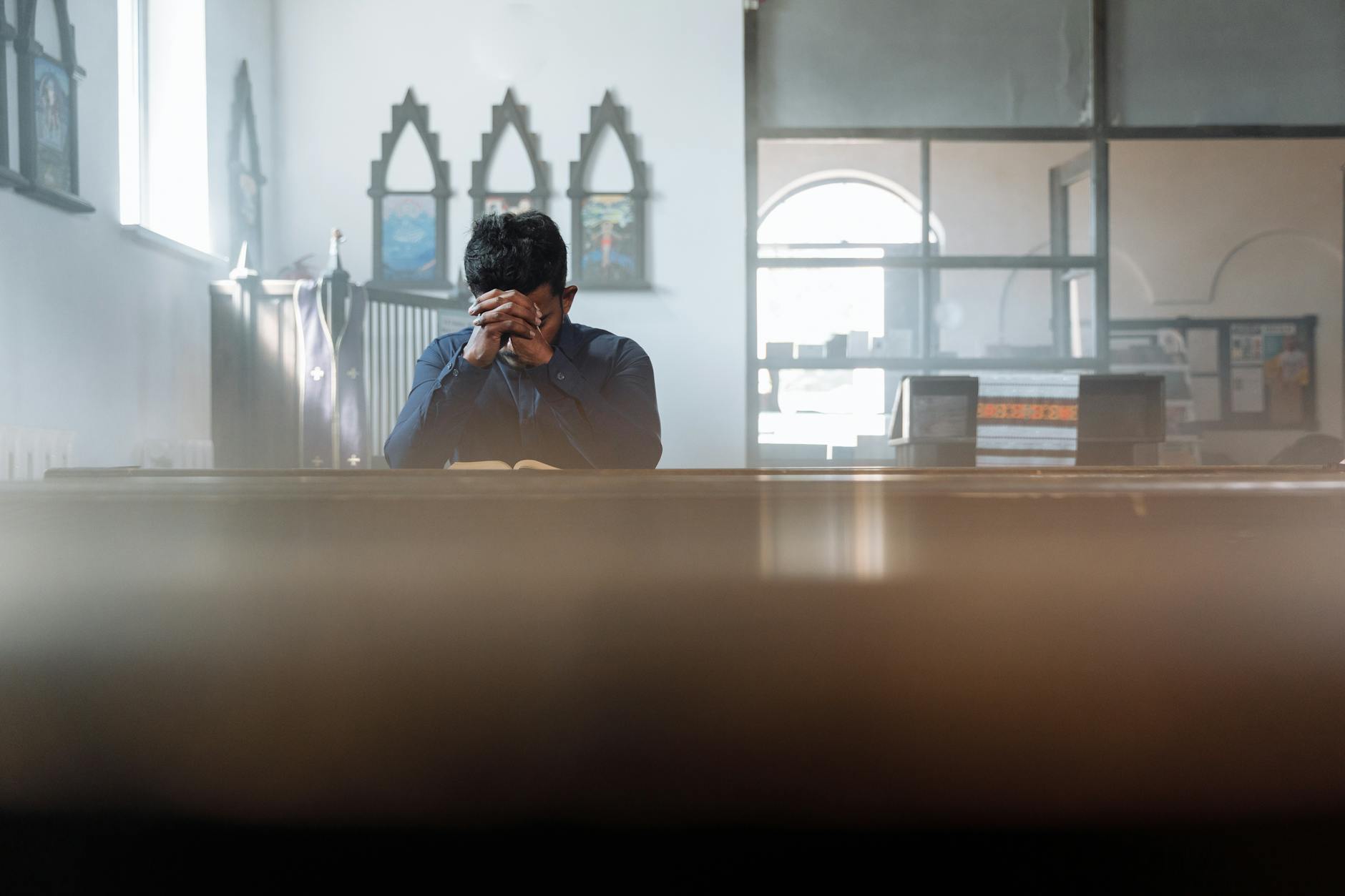 Mężczyzna pogrążony w modlitwie w słonecznym pokoju przed spowiedzią