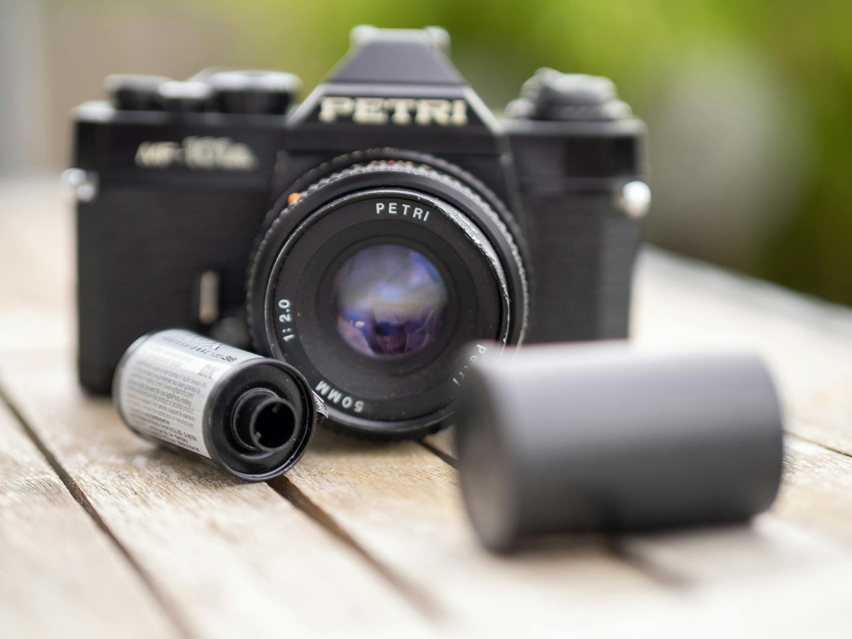 Analogowy aparat Petri z obiektywem i kliszą na drewnianym stole