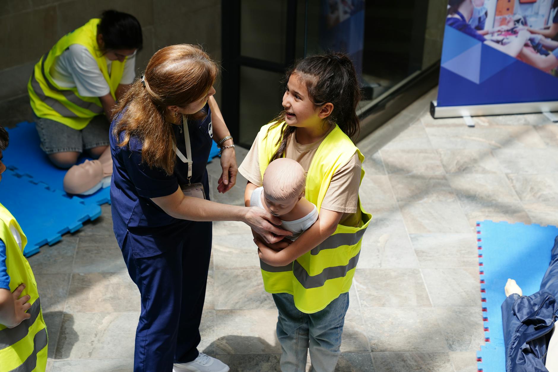 Instruktorka pokazuje dziecku na fantomie techniki pierwszej pomocy dla niemowlą