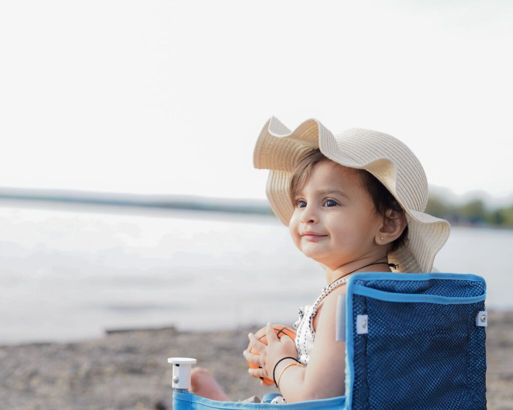 Niemowlę w kapeluszu siedzące na plaży nad morzem